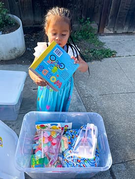 Small child taking learning materials and activities out of a clear plastic box