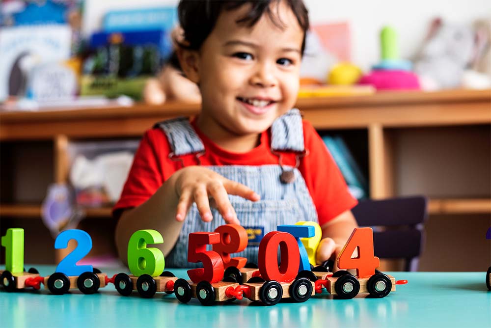 Child at a classroom table playing with a number train