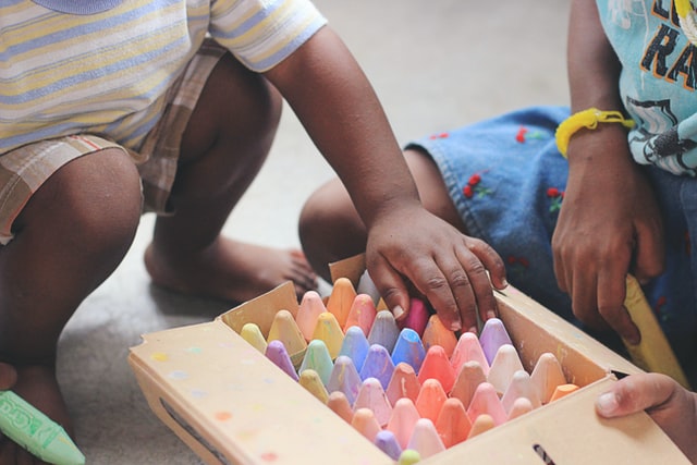 Two children crouched over a box of chalk